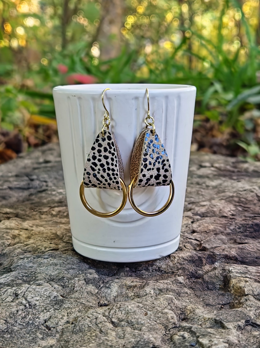 Pair of earrings with animal print design on a white cup against a natural background